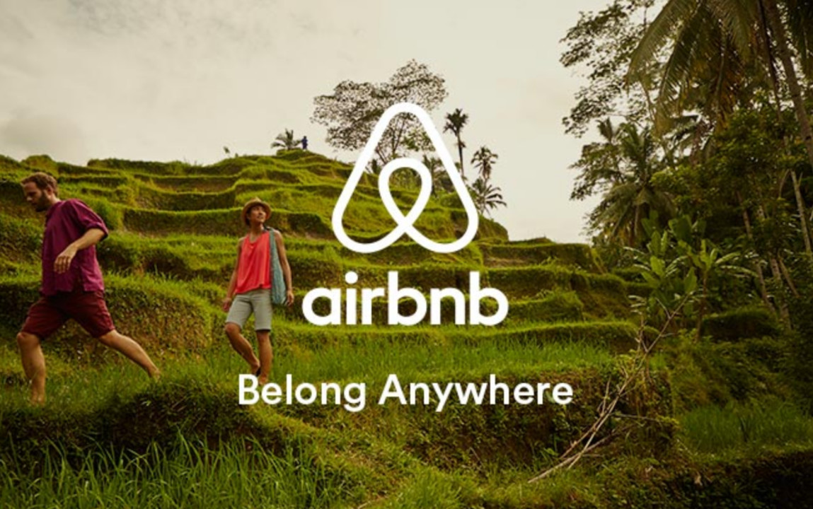 airbnb ad with belong anywhere tagline. scenery showing two people walking in a terraced rice field.