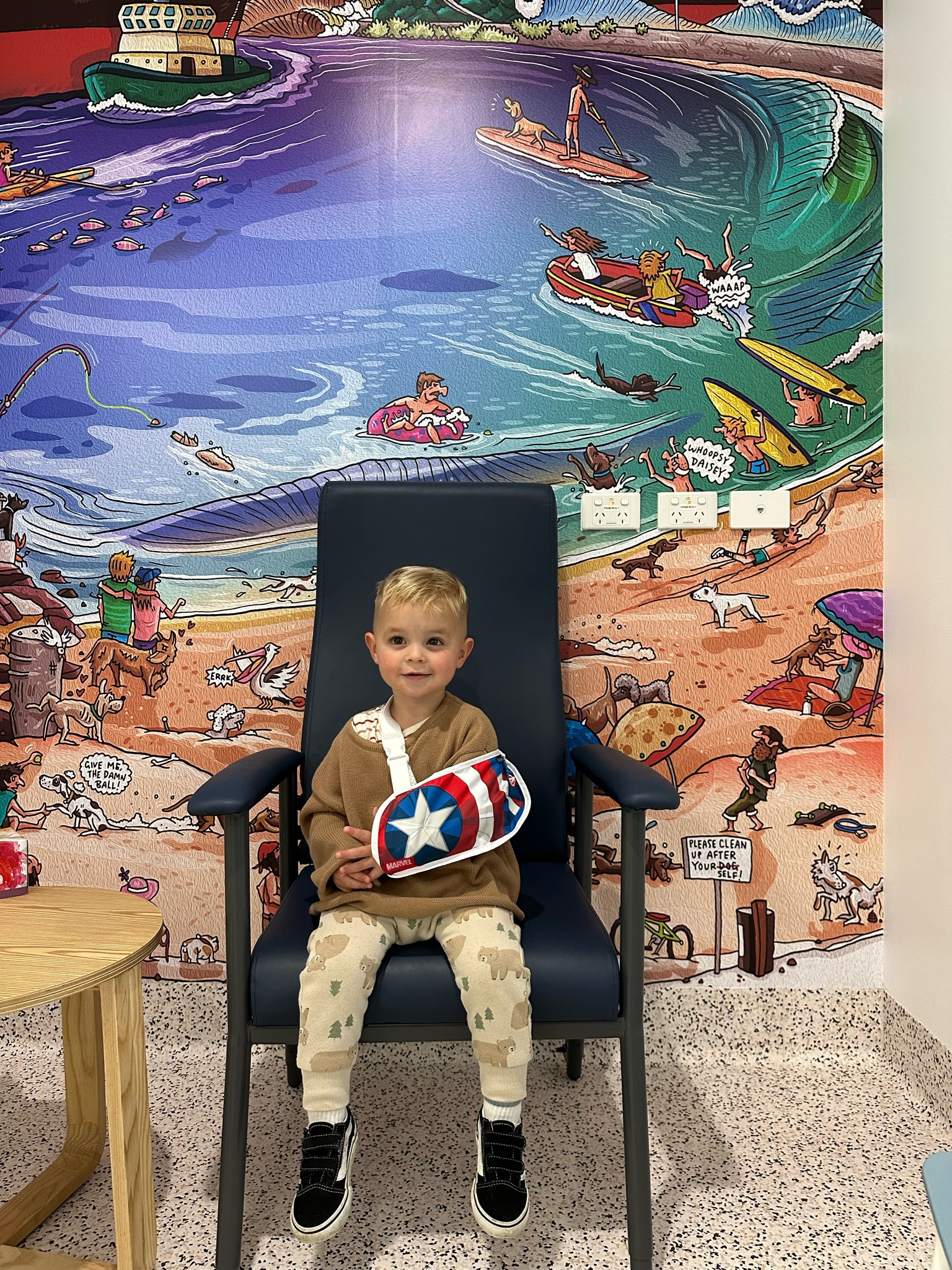 Boy with sling in front of mural wall of saline